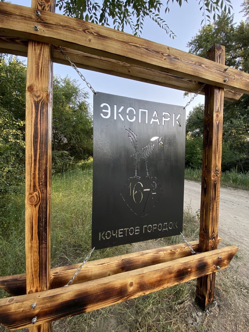 Знак экопарка «Кочетов городок» среди деревьев